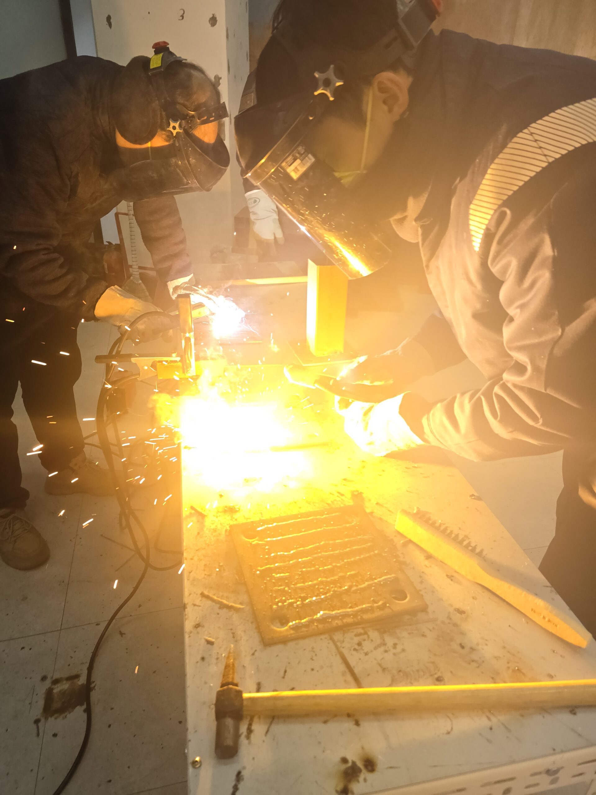 Korean shipyard workers welding steel hull plates with bright sparks and industrial cranes overhead